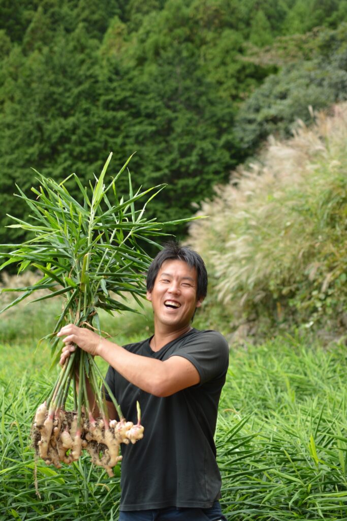 収穫した生姜を手に笑顔を見せるvege likeの安田裕志さん